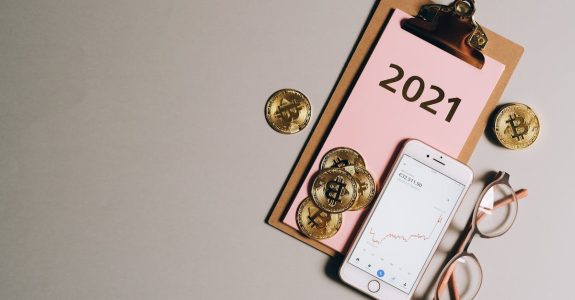 flat-lay-of-bitcoins-smartphone-eyeglasses-and-clipboard-with-2021-text-symbolizing-cryptocurren-1